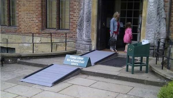 Twee drempels met opgangen voor rolstoelen, maar in het midden een bord “”Keep clear for wheelchair users” dat de toegang verspert